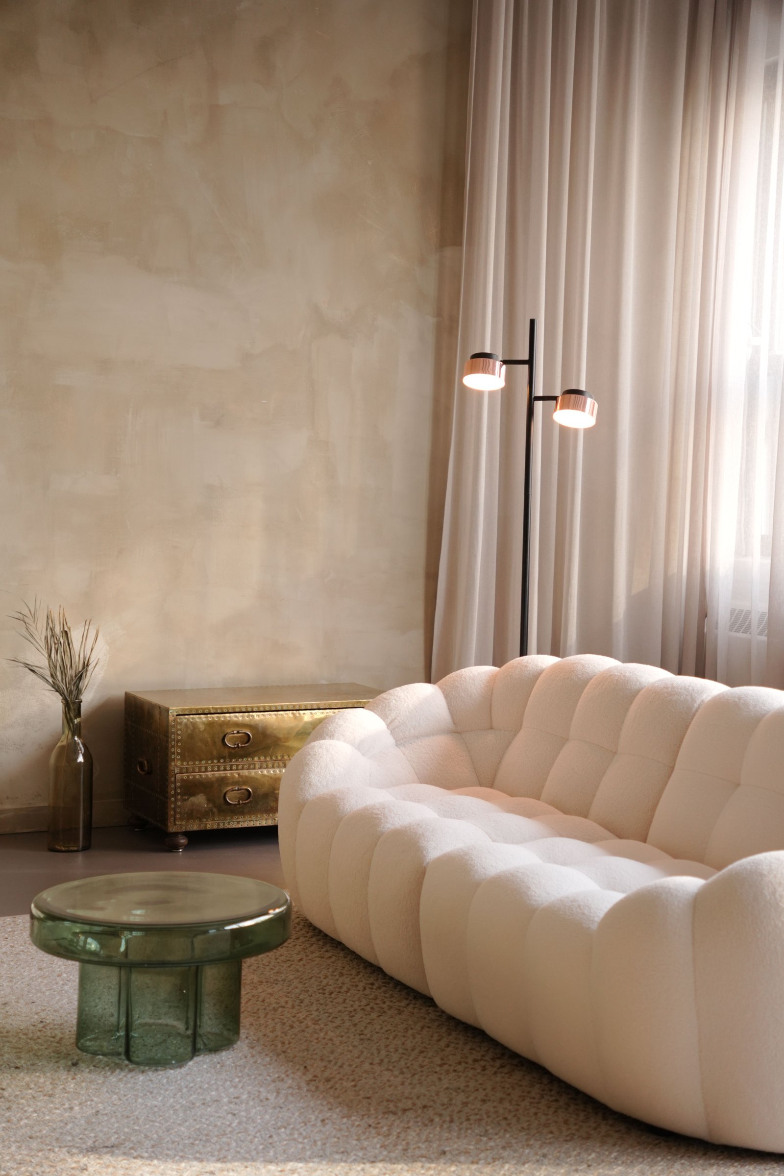 Cozy Japandi-style living room with soft sofa, warm plaster wall and layered lighting